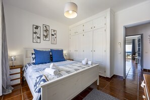 Ein Schlafzimmer mit Bett, Nachttischen, einem Kleiderschrank und Meerblick.