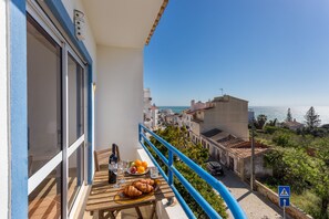 Ein Balkon mit Frühstückstisch, mit Blick auf eine Küstenstadt.