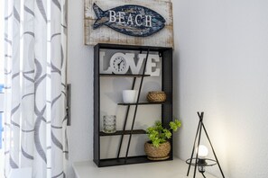 A wall with a decorative fish sign labeled 'BEACH' and a shelf with the word 'LOVE' and various items. - CoolHouses Algarve Luz | Delícia do Sol T2 (Luz)