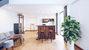 A modern kitchen with a central island, bar stools, and a dining table.