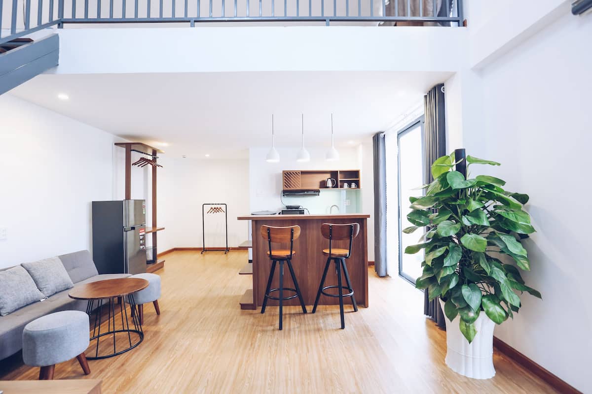 A modern kitchen with a central island, bar stools, and a dining table.