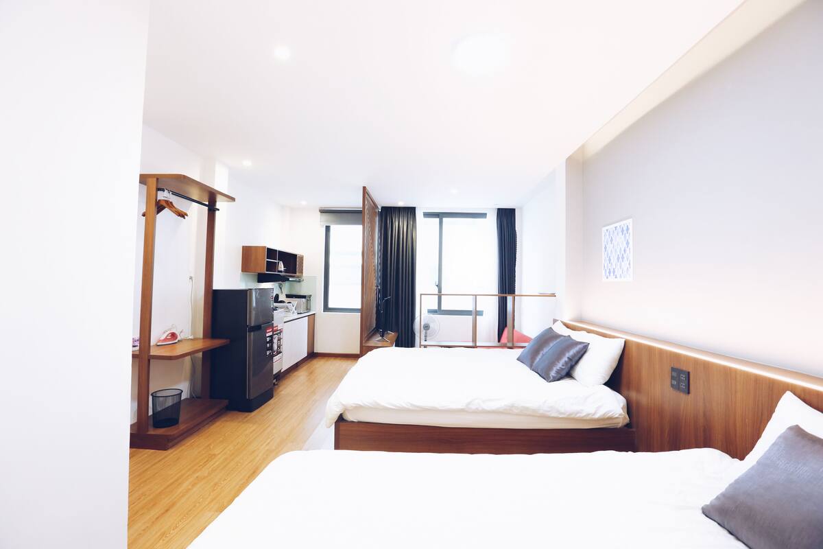Quarto de hotel com cama, escrivaninha, mini-geladeira e vista para o exterior.