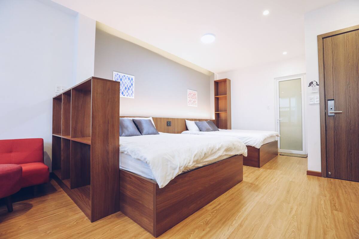 Quarto moderno com cama de madeira, uma cadeira vermelha e estantes embutidas.