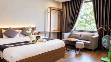 Ein Hotelzimmer mit Bett, Nachttisch, Lampe und einer Sitzecke mit Tisch und Stühlen.