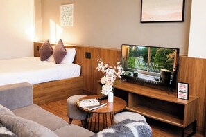A hotel room with a bed, a TV, a sofa, a coffee table, and a small bookshelf. - TTR Studio Apart Hotel (Cam Ly - Da Lat)