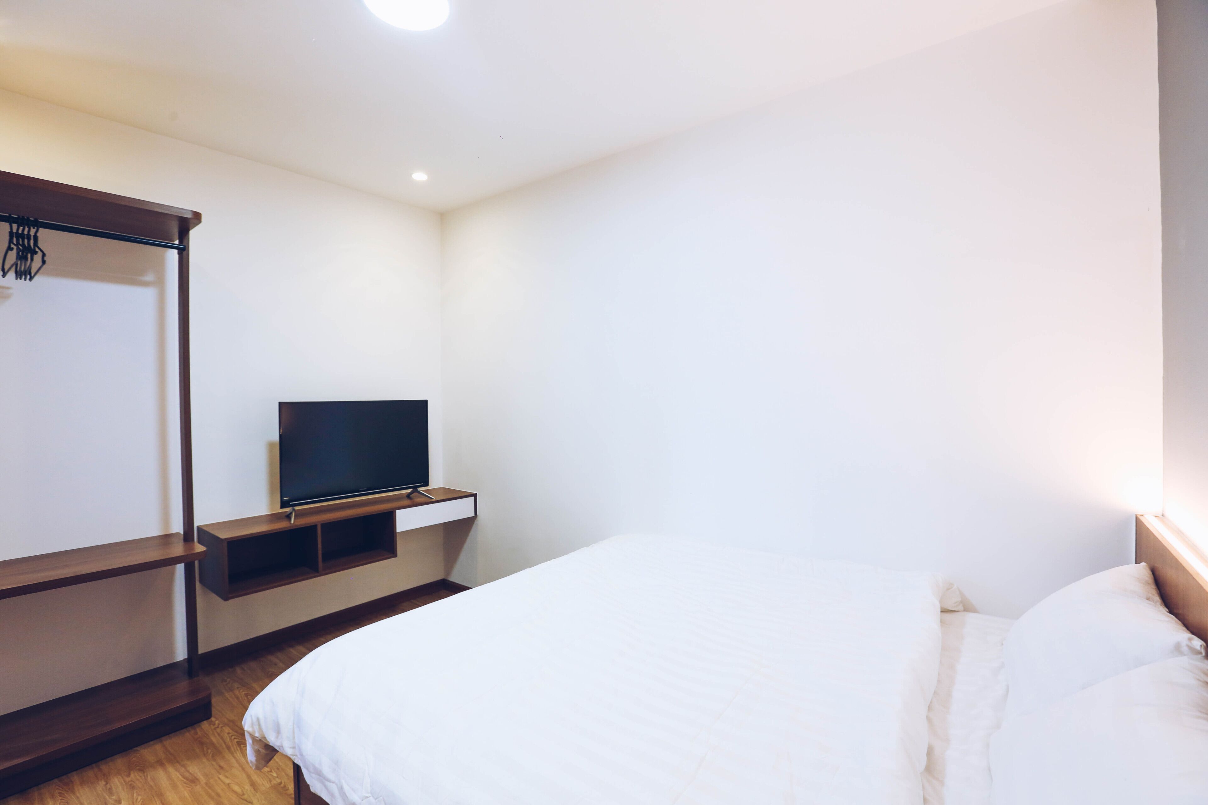 Ein Schlafzimmer mit einem Bett, einem Fernseher auf einem Regal und einem Kleiderschrank.