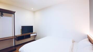 Ein Schlafzimmer mit einem Bett, einem Fernseher auf einem Regal und einem Kleiderschrank.
