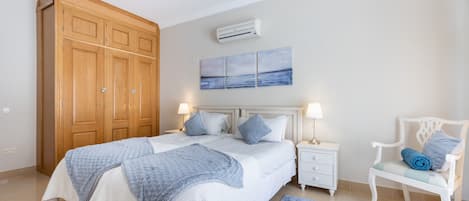 Quarto com cama grande, mesas de cabeceira, uma cadeira e guarda-roupa.