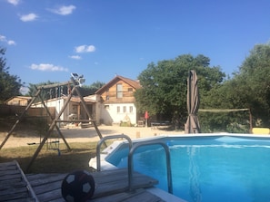 Une piscine avec une terrasse en bois et un ballon de football.