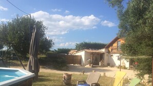 A wooden deck with lounge chairs, a hot tub, and a rustic building in the background. - 110m2 house + pool, No neighbors, in the countryside between Uzès and Cévennes (Occitanie)