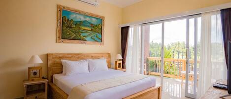 Quarto com uma cama grande, um quadro, ar-condicionado, mesa de cabeceira, abajur e varanda com vista.