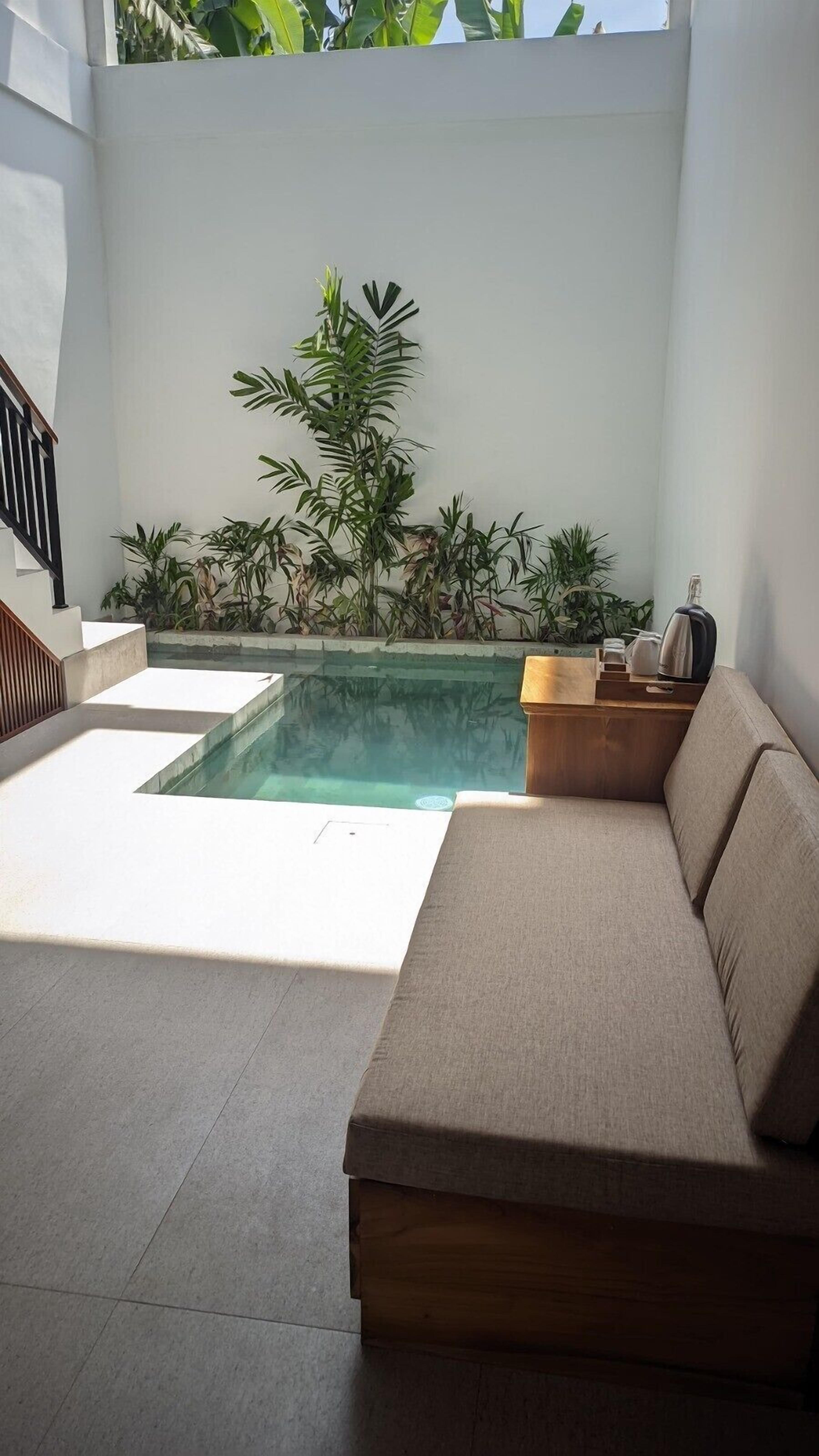 Een modern buitenverblijf met een zwembad, een houten bank en een beige banksofa.