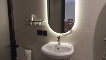 Ein Badezimmer mit einem weißen Waschbecken, einem Spiegel mit ovalem Rahmen und einer Toilette.