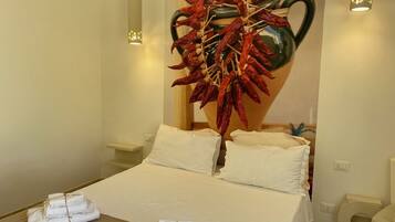 Ein Hotelzimmer mit einem Bett, zwei Nachttischen, einer an der Wand befestigten Vase mit getrockneten roten Chilischoten und zwei Wandleuchten.