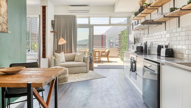 Eine moderne Wohnung mit Küche, Essbereich und Wohnzimmer. Sie verfügt über ein großes Fenster, einen Balkon und Blick auf die Stadt.