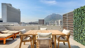 Eine Dachterrasse mit Holztisch und -stühlen, einer Sitzecke und einer grünen Wand.