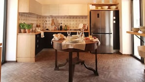 A modern kitchen with a wooden ceiling, a chandelier, and a dining table set for a meal.