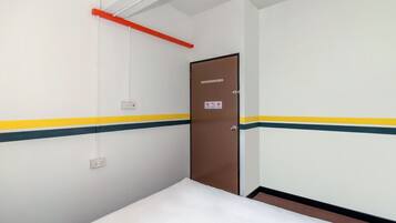 A hotel room with a bed, a door, and a light fixture.