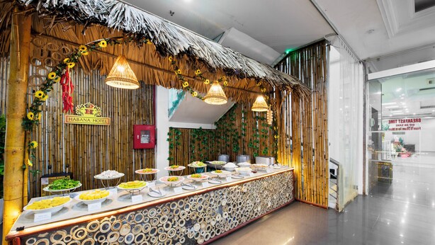 A buffet area with a tropical theme, featuring a thatched roof and bamboo wall decorations.