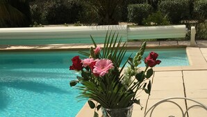 Desayuno junto a una piscina con cruasanes, fruta, jamón y jugo.