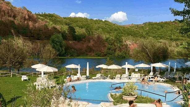 A pool area with multiple swimming pools, lounge chairs, and umbrellas.