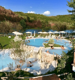 A pool area with multiple swimming pools, lounge chairs, and umbrellas.