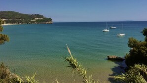 A coastal view with clear turquoise waters, boats, and a rocky shoreline with vegetation.