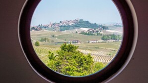 A view through a window of a rural landscape with vineyards, a hilltop village, and a clear sky. - Lovely apartment for 2 people with pool, WIFI, TV, patio and pets allowed (La Morra)