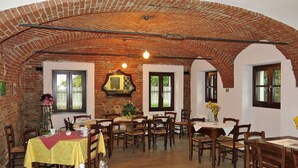 A dining area with brick arches, wooden tables, and chairs. - Lovely apartment for 2 people with pool, WIFI, TV, patio and pets allowed (La Morra)