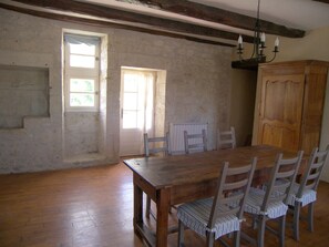 A dining room with a wooden table and chairs, a staircase, and a wooden cabinet.
