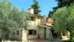 A stone house with a chimney, a small porch, and a garden with olive trees. - Nice apartment in villa for 6 people with pool, WIFI, TV and terrace (Atessa)