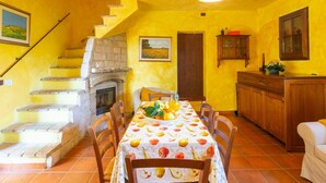 A dining area with a table set for four, a fireplace, and a staircase leading to an upper level. - Nice apartment in villa for 6 people with pool, WIFI, TV and terrace (Atessa)