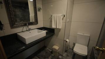 A modern bathroom with a white sink, black countertop, and a toilet.
