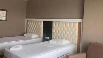 A hotel room with two beds, a chair, and a wall-mounted artwork.