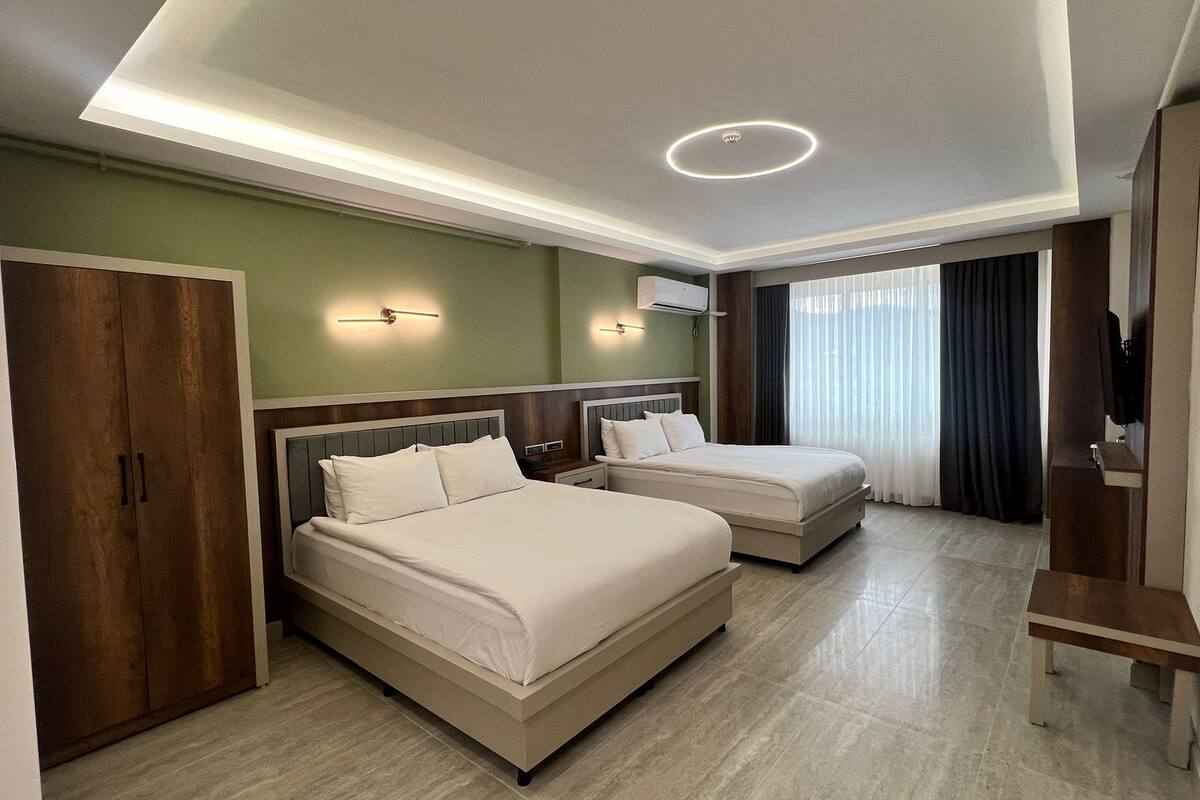 Ein Hotelzimmer mit zwei Betten, einem Kleiderschrank, einem Fernseher und einer Deckenleuchte.