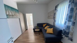 Uma sala de estar moderna com um sofá azul escuro, uma mesa redonda pequena e um quadro na parede.