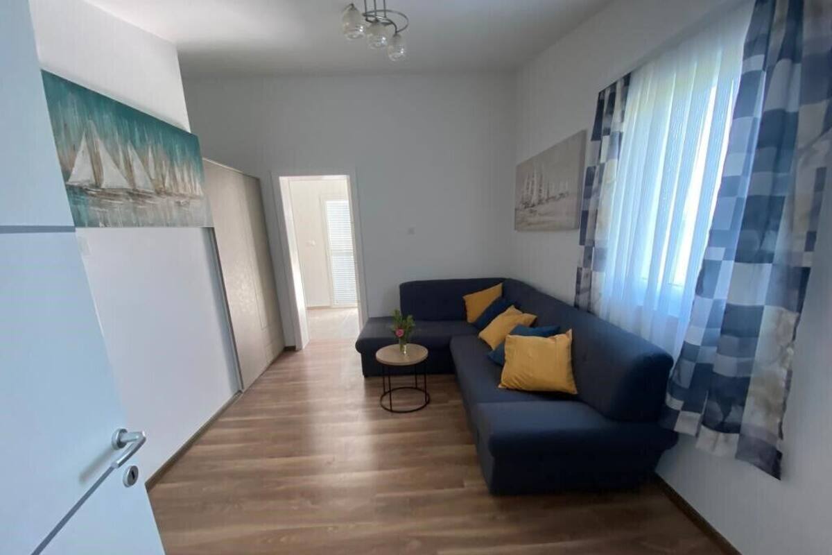 Ein modernes Wohnzimmer mit einem dunkelblauen Sofa, einem kleinen runden Tisch und einem Bild an der Wand.