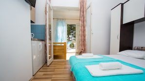 Quarto com duas camas, piso de madeira, banheiro com chuveiro e varanda com vista.