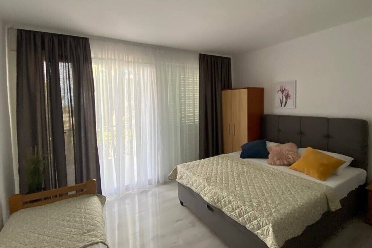 Ein Schlafzimmer mit zwei Betten, einem Kleiderschrank und einem großen Fenster mit Vorhängen.