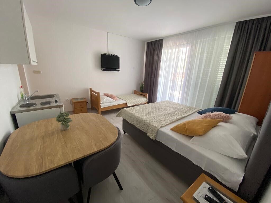 Een hotelkamer met een bed, een bureau, een stoel, een televisie en een raam met gordijnen.