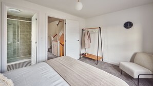 Ein Schlafzimmer mit Bett, Hängesessel, Kleiderständer und Duschbereich.