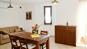 Un comedor con una mesa y sillas de madera, un sofá, un armario y dos lámparas colgantes.