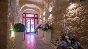A stone-walled corridor with a patterned floor, leading to a door with a red frame. - 39 St. George (Victoria)