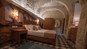 A bedroom with a checkered floor, a bed with pillows, wooden furniture, and stone walls. - 39 St. George (Victoria)