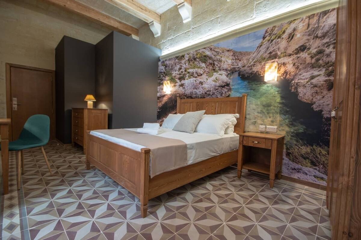 Une chambre à coucher comprenant un lit, une table de chevet, une chaise et une fresque murale.