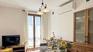 Ein Essbereich mit einem Holztisch, gedeckt für zwei Personen, einem Fernseher auf einem Schrank und einer großen Kommode mit Milchglas-Türen.