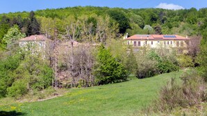 Ein Landhaus mit rotem Dach, umgeben von einem grünen Feld und Bäumen.