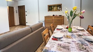 Un'area pranzo con un tavolo lungo apparecchiato per quattro persone, una panca e un armadietto in legno sullo sfondo.