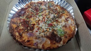 Pizza con diferentes ingredientes en una caja de cartón.