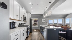 A modern kitchen with white cabinets, a central island, and a view of the outside.